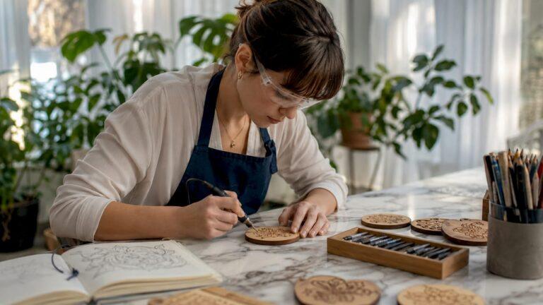 Woman engraving wooden coaster at craft table