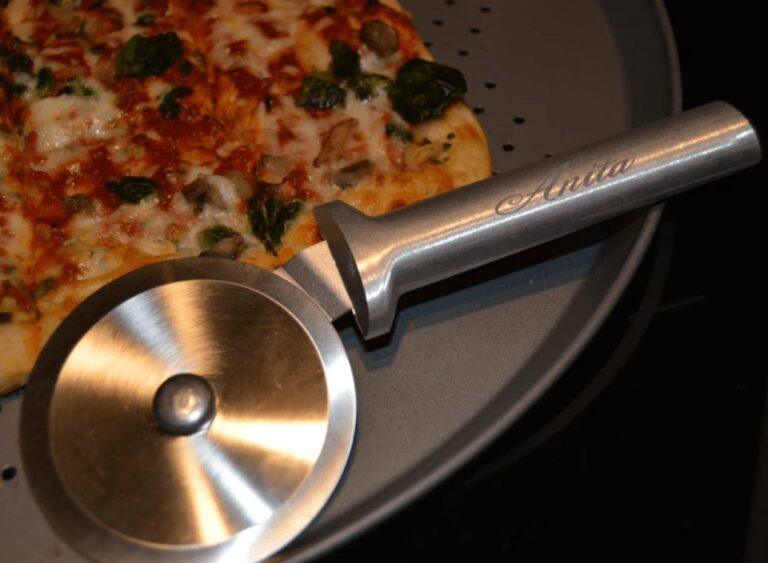 Personalized RADA pizza cutter with laser-engraved handle from Signature Laser Designs, shown slicing a pizza