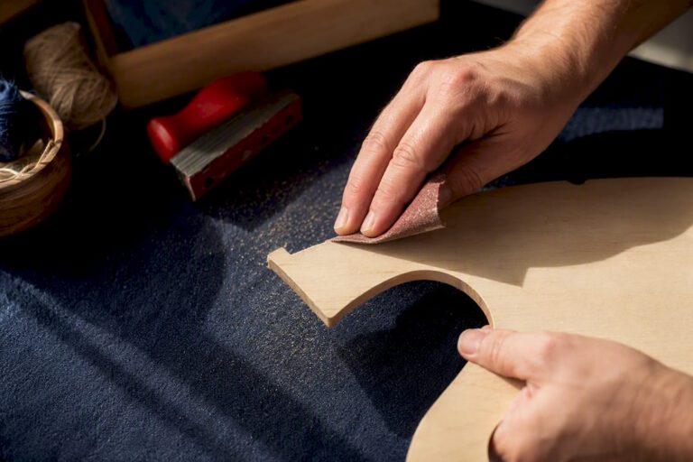 Hands sanding an unfinished wood cutout