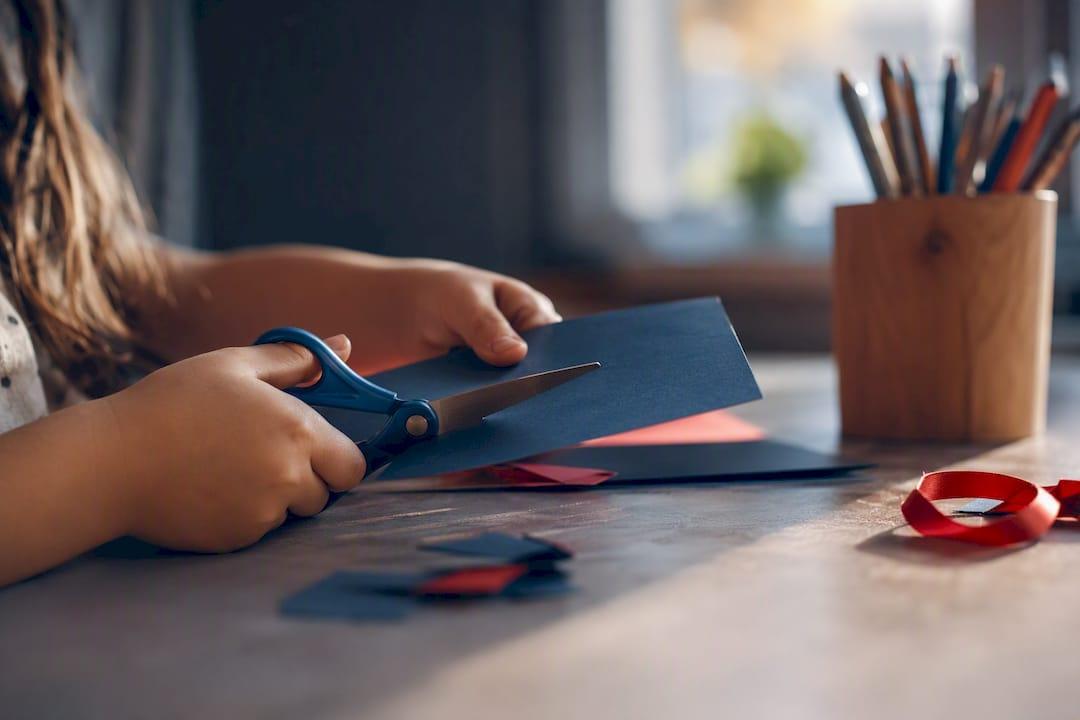 Child using personalized scissors at craft table