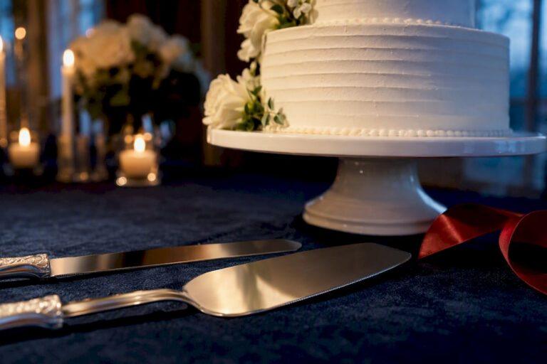 Cropped engraved cake knife and server beside wedding cake