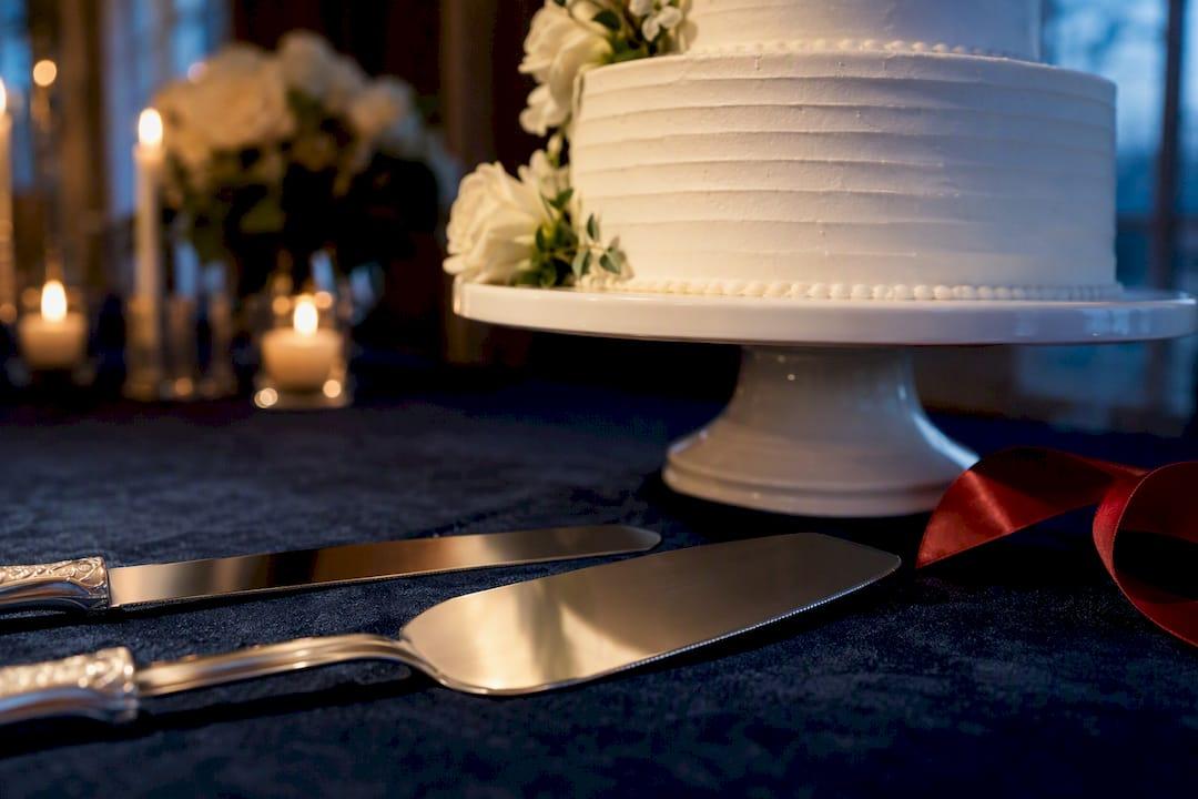 Cropped engraved cake knife and server beside wedding cake