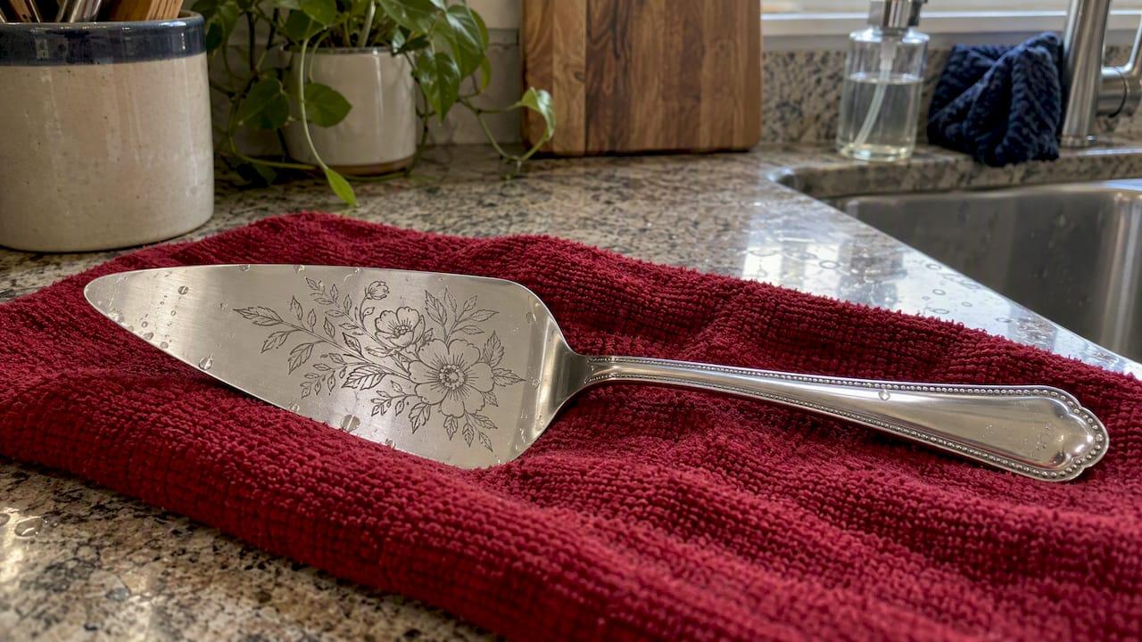 Laser-etched pie server drying on crimson cloth