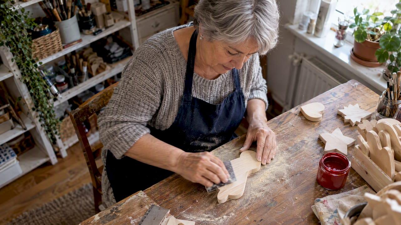 Manos lijando recortes de madera antes de pintarlos