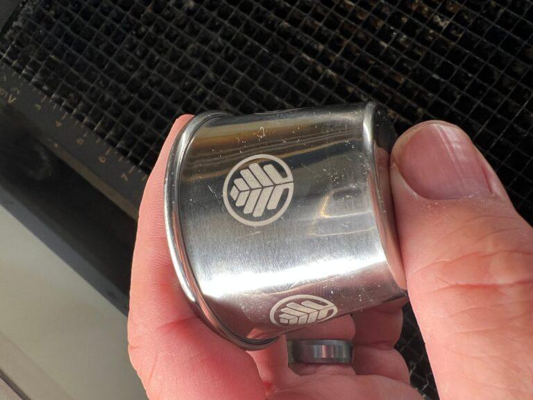Industrial laser engraving of a company logo on a stainless steel part